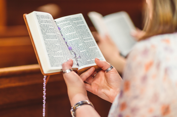 Woman reading Bible with a Rosary